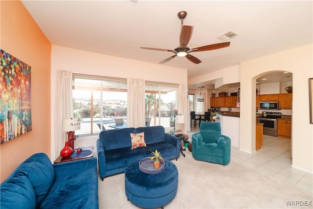 living area featuring a ceiling fan, arched walkways, visible vents, and light tile patterned flooring