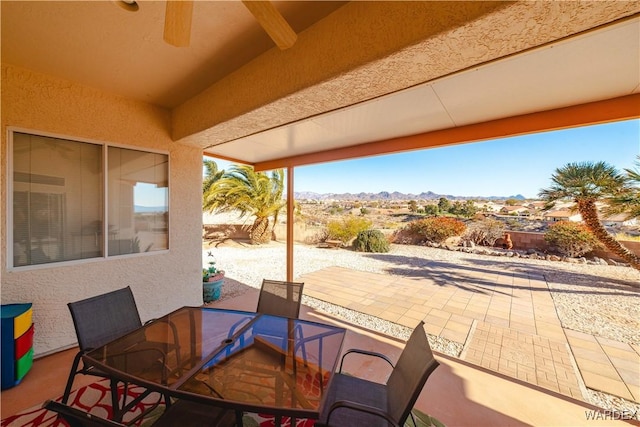 view of patio featuring outdoor dining area, ceiling fan, and a mountain view