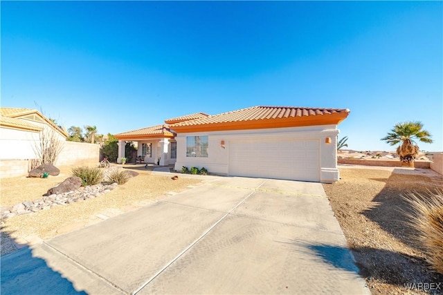 mediterranean / spanish-style house featuring concrete driveway, a tile roof, an attached garage, and stucco siding