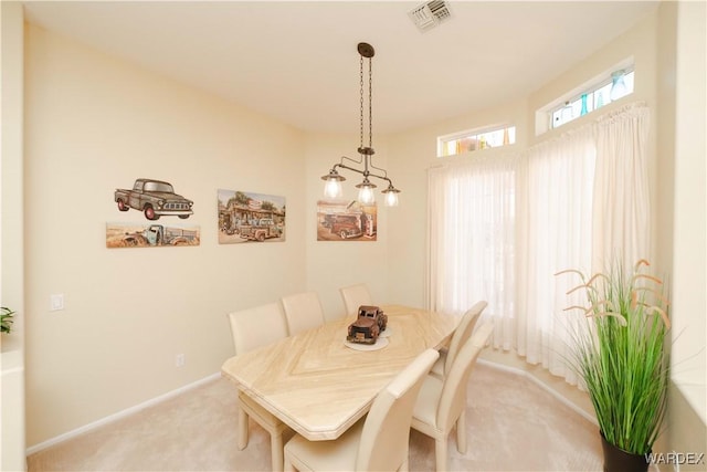 carpeted dining space with baseboards and visible vents