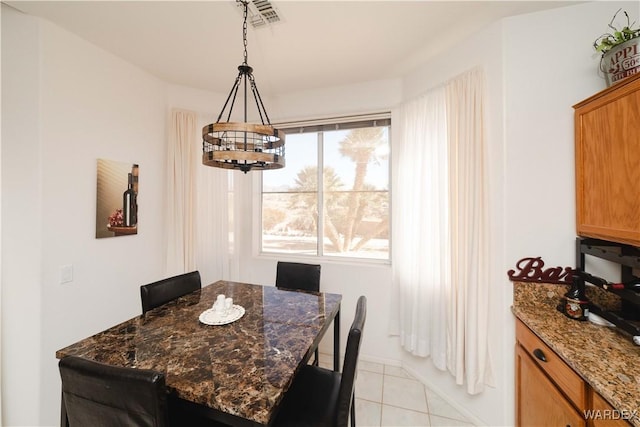 dining space with light tile patterned floors, visible vents, and an inviting chandelier