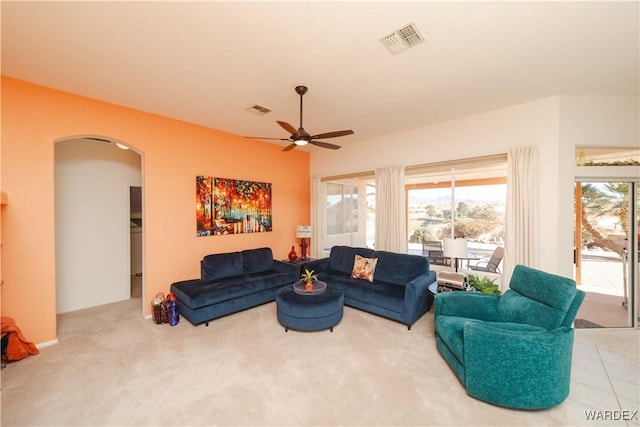 carpeted living area featuring arched walkways, visible vents, and ceiling fan