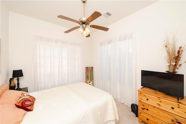 bedroom featuring ceiling fan, visible vents, and light colored carpet