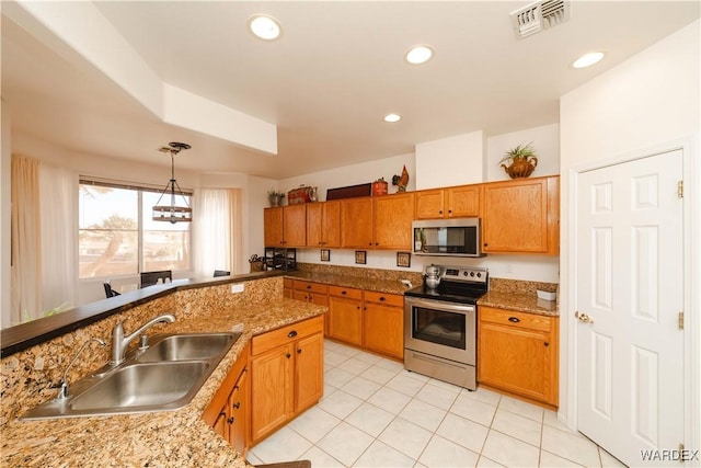 kitchen with a sink, visible vents, appliances with stainless steel finishes, brown cabinets, and pendant lighting