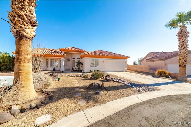 mediterranean / spanish home featuring concrete driveway, a tile roof, an attached garage, and stucco siding