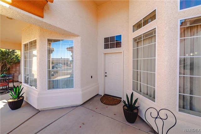 doorway to property with ceiling fan, a patio, and stucco siding