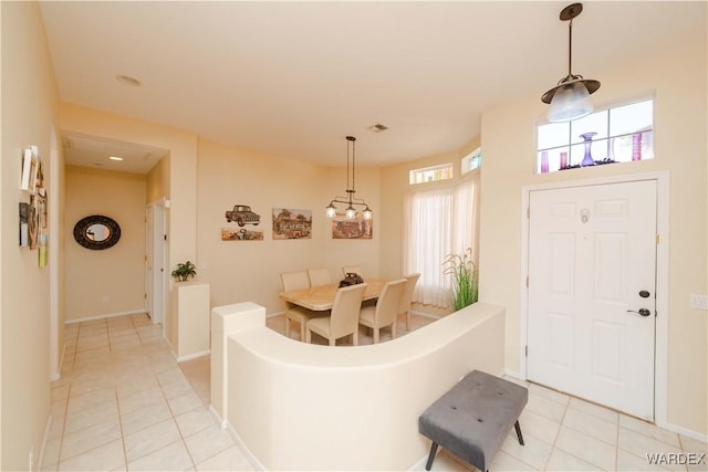 foyer with a wealth of natural light, light tile patterned flooring, visible vents, and baseboards