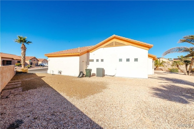 rear view of house featuring central air condition unit, a tiled roof, a residential view, and stucco siding