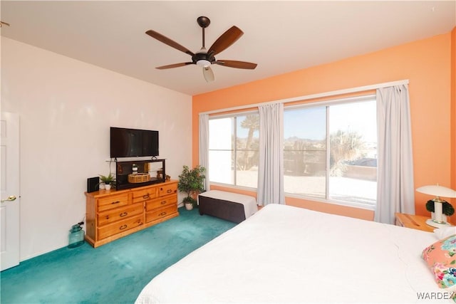 bedroom featuring multiple windows, dark carpet, and a ceiling fan