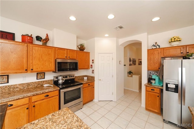 kitchen with arched walkways, stainless steel appliances, recessed lighting, visible vents, and light stone countertops