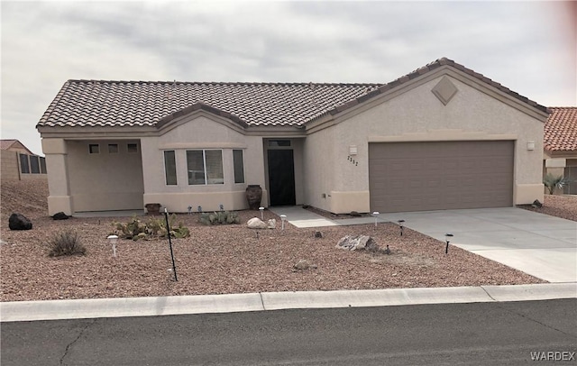 view of front of property with driveway, an attached garage, a tiled roof, and stucco siding