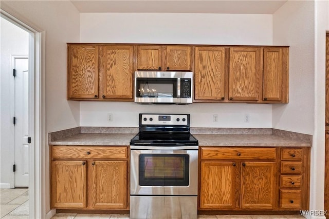 kitchen featuring stainless steel appliances, light countertops, and brown cabinets