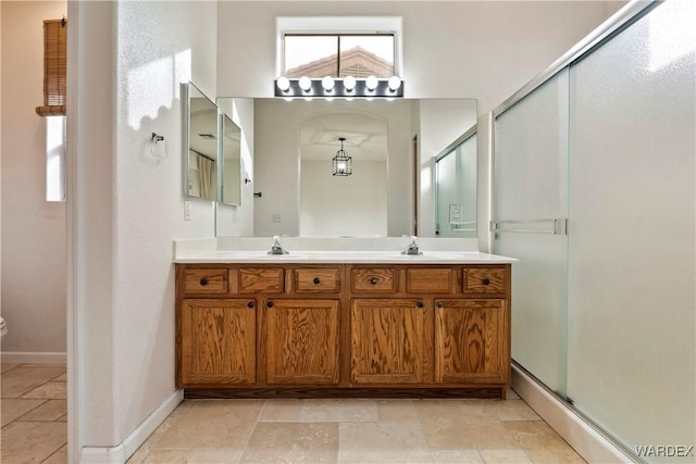 bathroom with a sink, a shower stall, baseboards, and double vanity