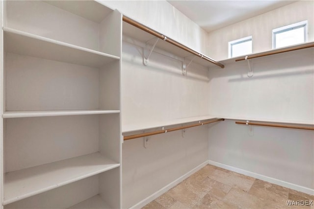 walk in closet featuring stone finish floor