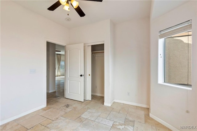 unfurnished bedroom with a ceiling fan, stone tile floors, baseboards, and a closet