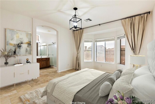 bedroom with baseboards, visible vents, arched walkways, ensuite bath, and stone tile flooring