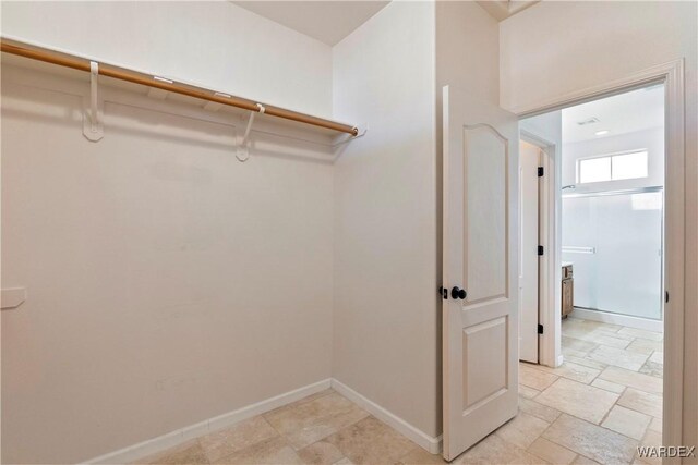 walk in closet featuring stone finish flooring