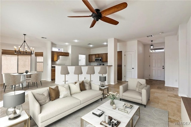 living area featuring visible vents, baseboards, and ceiling fan with notable chandelier