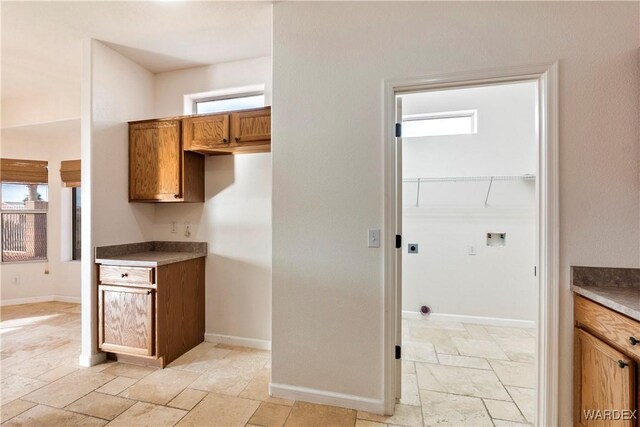 kitchen featuring baseboards, brown cabinets, and stone tile floors