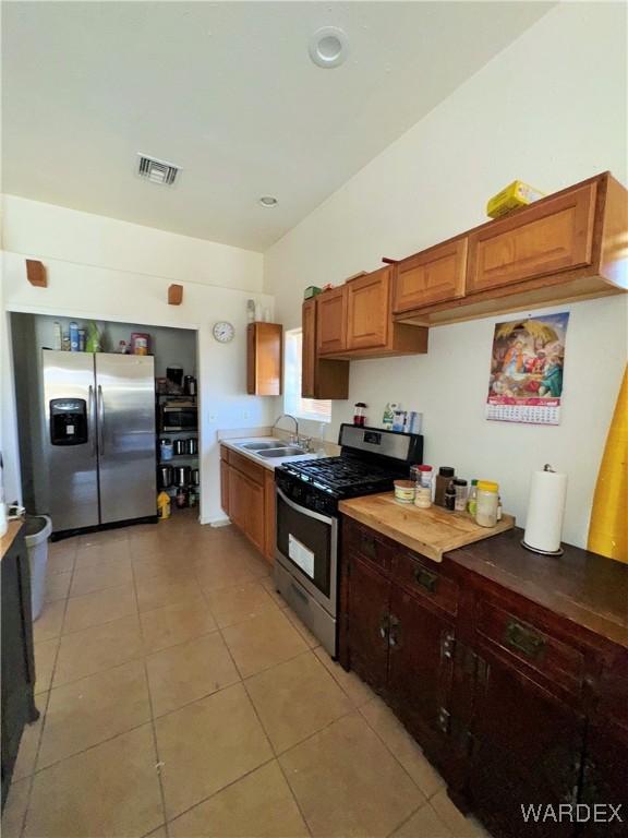 kitchen with light tile patterned floors, a sink, visible vents, and stainless steel appliances