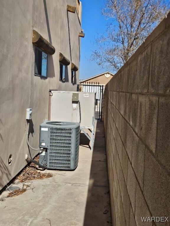 view of property exterior featuring central AC, fence, and stucco siding