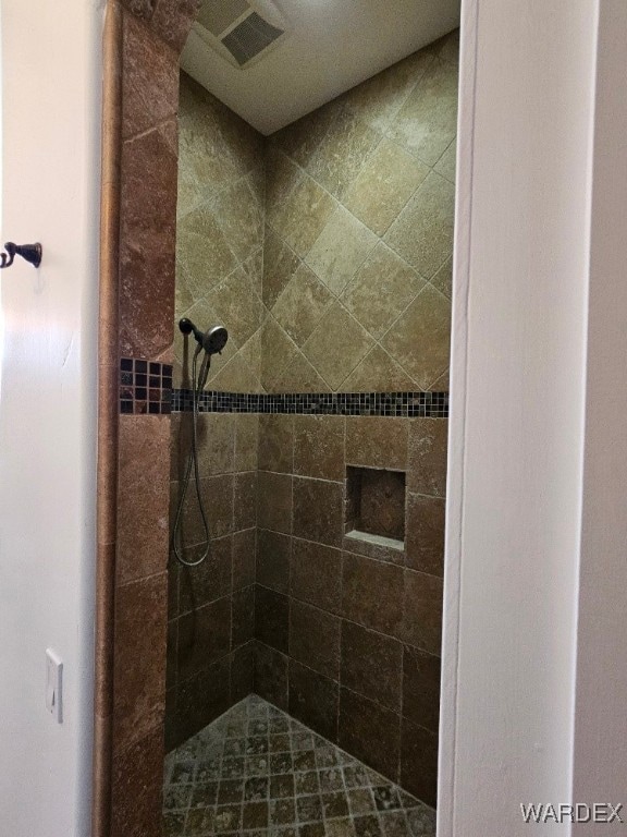 full bathroom featuring a tile shower and visible vents