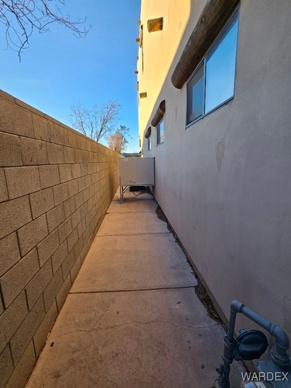 view of side of home with a patio area, fence, and stucco siding