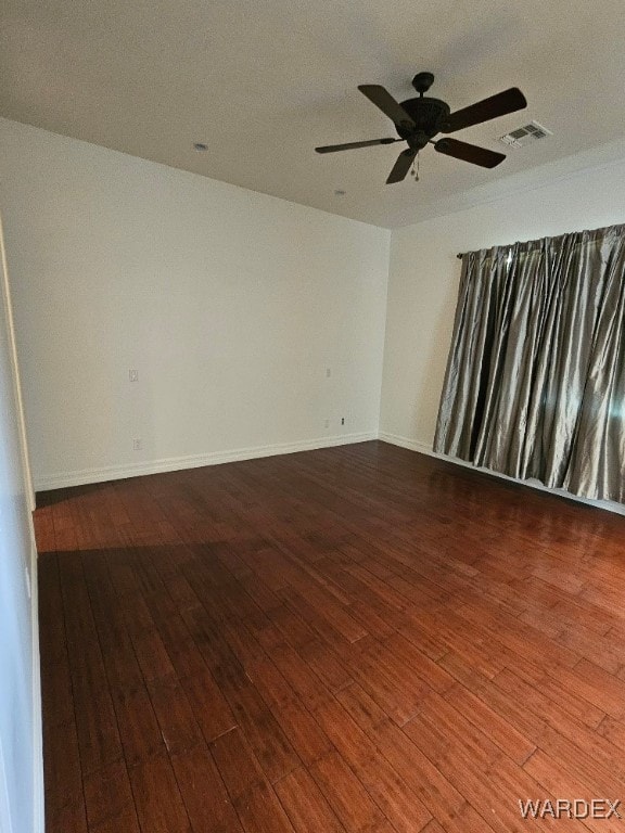 spare room featuring ceiling fan, dark wood-style flooring, visible vents, and baseboards