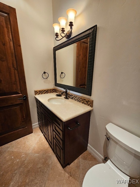 bathroom with toilet, vanity, and baseboards