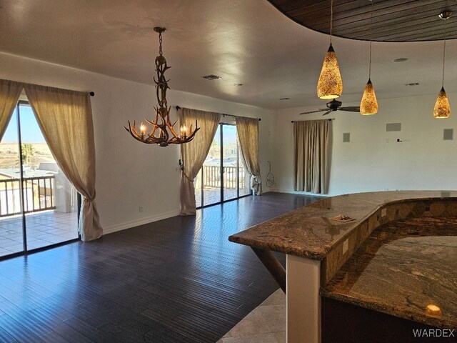 interior space with baseboards, visible vents, dark wood-type flooring, hanging light fixtures, and an inviting chandelier