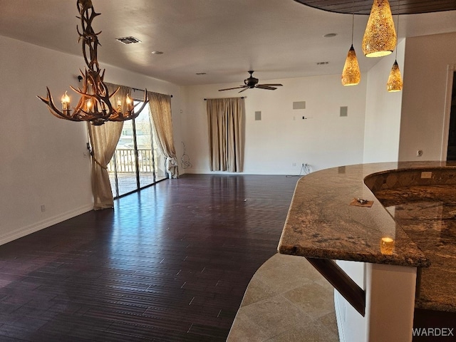 unfurnished living room featuring baseboards, dark wood finished floors, visible vents, and a ceiling fan