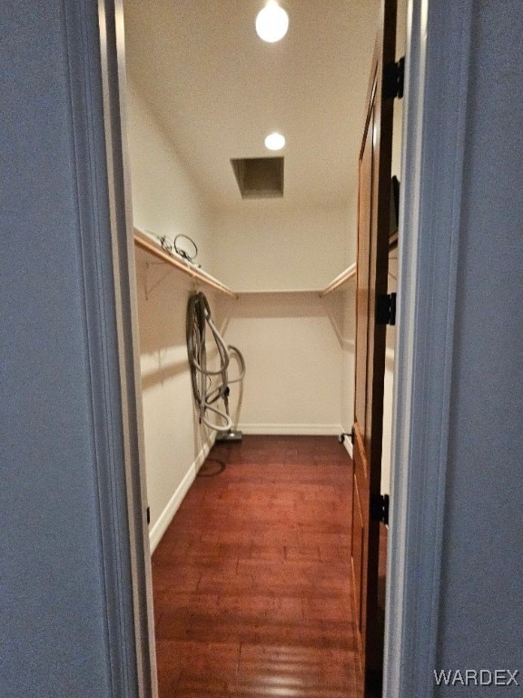 walk in closet with dark wood-type flooring