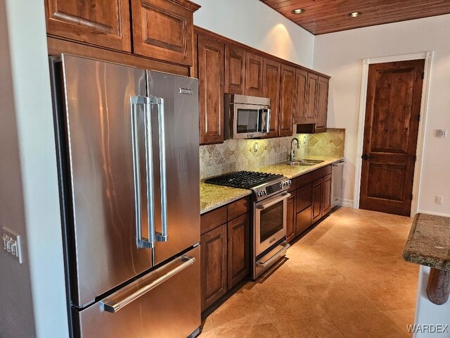 kitchen with recessed lighting, stainless steel appliances, a sink, light stone countertops, and tasteful backsplash