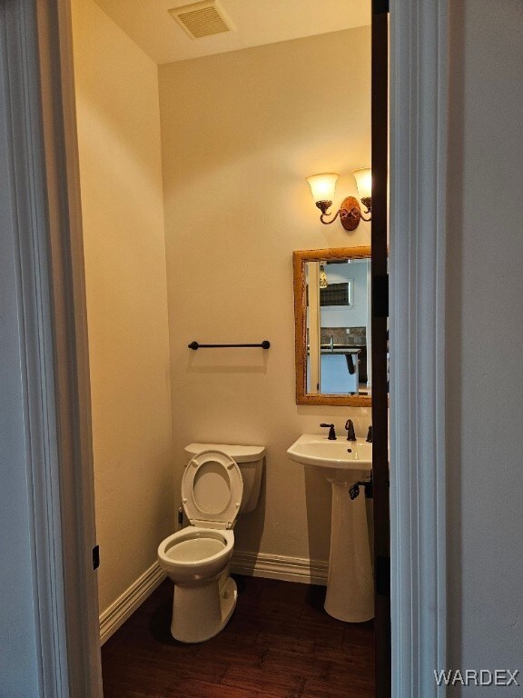 bathroom with baseboards, visible vents, toilet, and wood finished floors