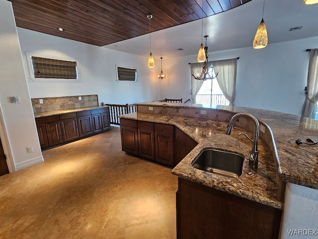 kitchen featuring decorative light fixtures, a sink, visible vents, and dark brown cabinets