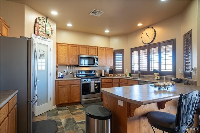 kitchen featuring recessed lighting, stainless steel appliances, a peninsula, a sink, and visible vents