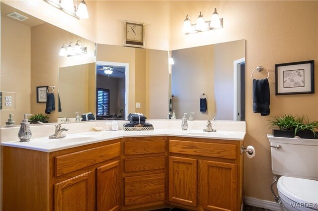 bathroom featuring toilet, double vanity, and a sink