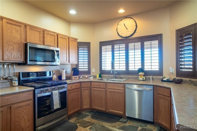 kitchen featuring recessed lighting, a sink, light countertops, appliances with stainless steel finishes, and stone finish floor