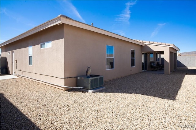 rear view of property with a patio area, cooling unit, and stucco siding