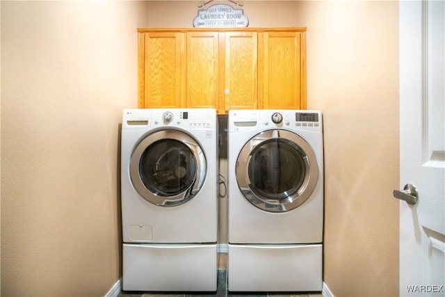 laundry room featuring washer and clothes dryer, cabinet space, and baseboards