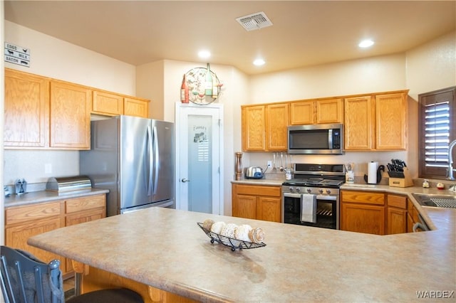 kitchen with stainless steel appliances, recessed lighting, visible vents, and a kitchen breakfast bar