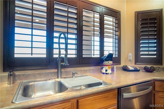 kitchen featuring a sink, brown cabinets, stainless steel dishwasher, and light countertops