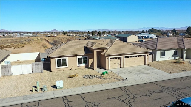 single story home featuring driveway, a tile roof, an attached garage, fence, and a mountain view