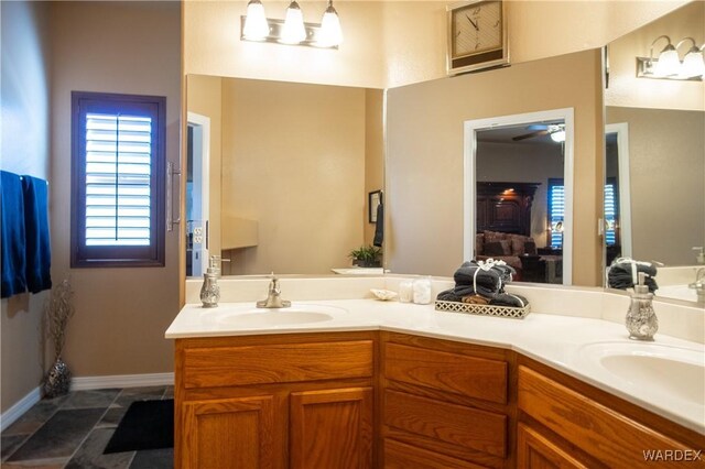 bathroom with double vanity, a sink, and baseboards