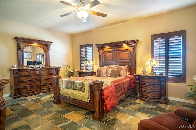 bedroom featuring stone finish floor, ceiling fan, and baseboards