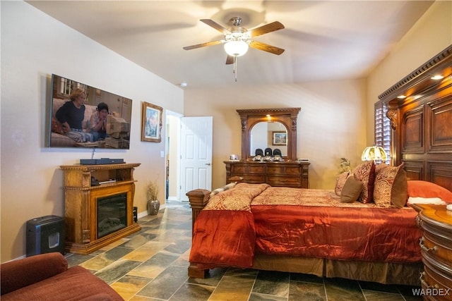 bedroom featuring ceiling fan and a glass covered fireplace