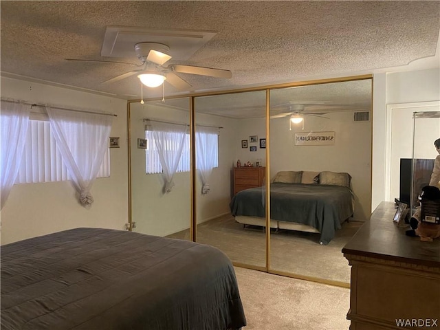 carpeted bedroom with a ceiling fan, a closet, visible vents, and a textured ceiling