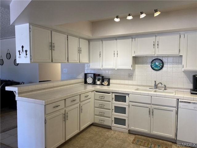 kitchen featuring dishwasher, a peninsula, tile counters, and white cabinets