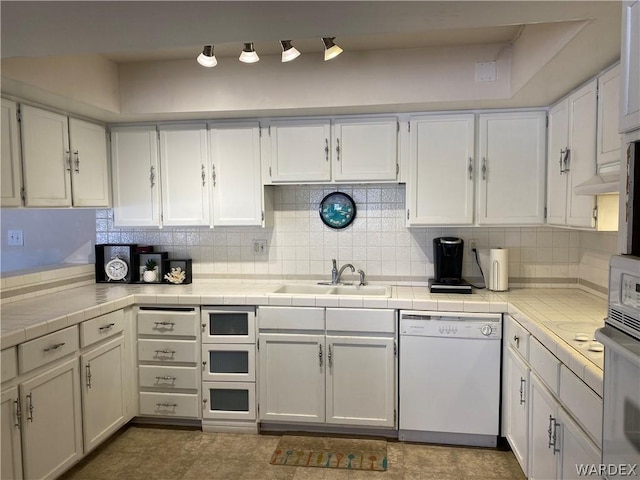 kitchen featuring tile countertops, a sink, white cabinetry, decorative backsplash, and dishwasher