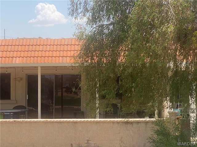 rear view of house with a tile roof and stucco siding